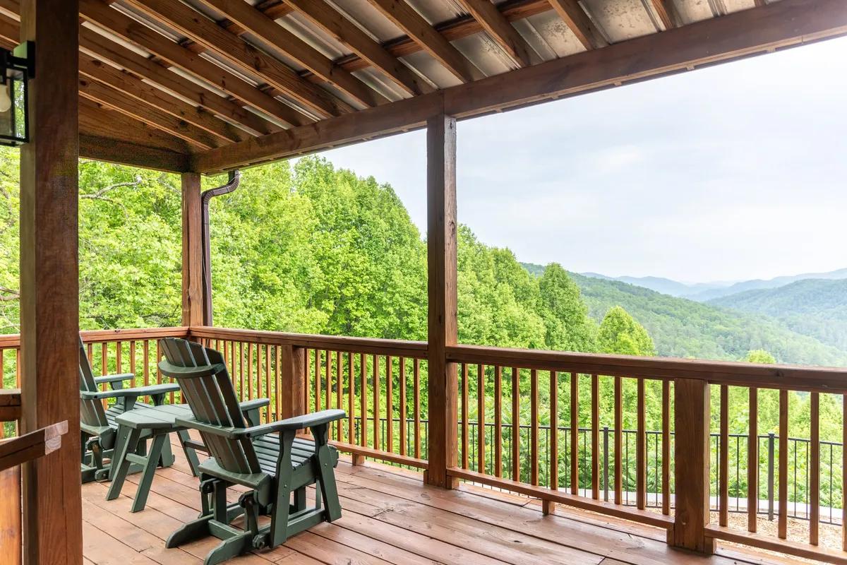 This image displays a wooden deck furnished with classic rocking chairs and a breathtaking mountain view. The deck overlooks expansive natural scenery, inviting guests to relax while soaking in the tranquil ambiance and stunning vistas.