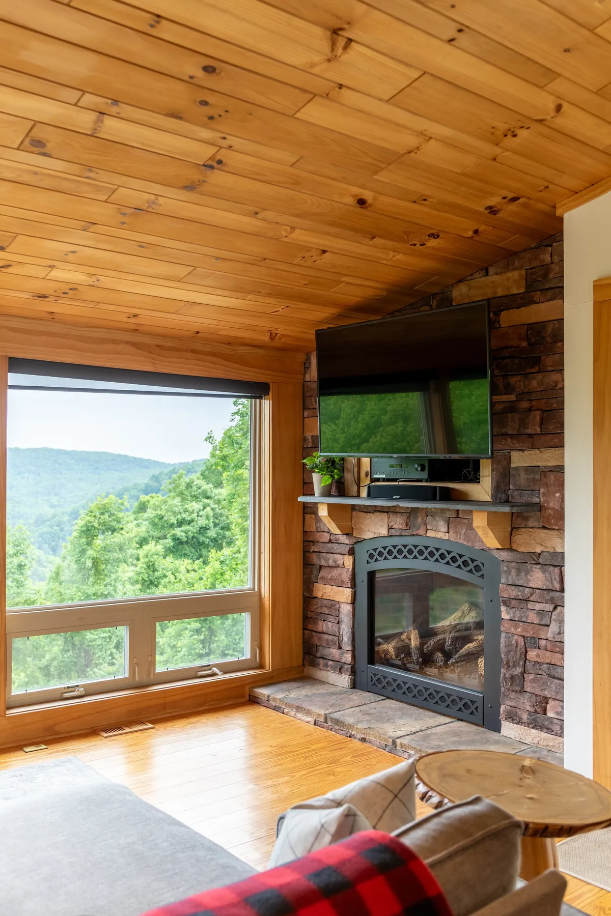 A warm, inviting living area with a fireplace, large window views, a television, and a comfortable seating setup. The scene is ideal for unwinding, watching movies, or spending cozy evenings with family and friends.
